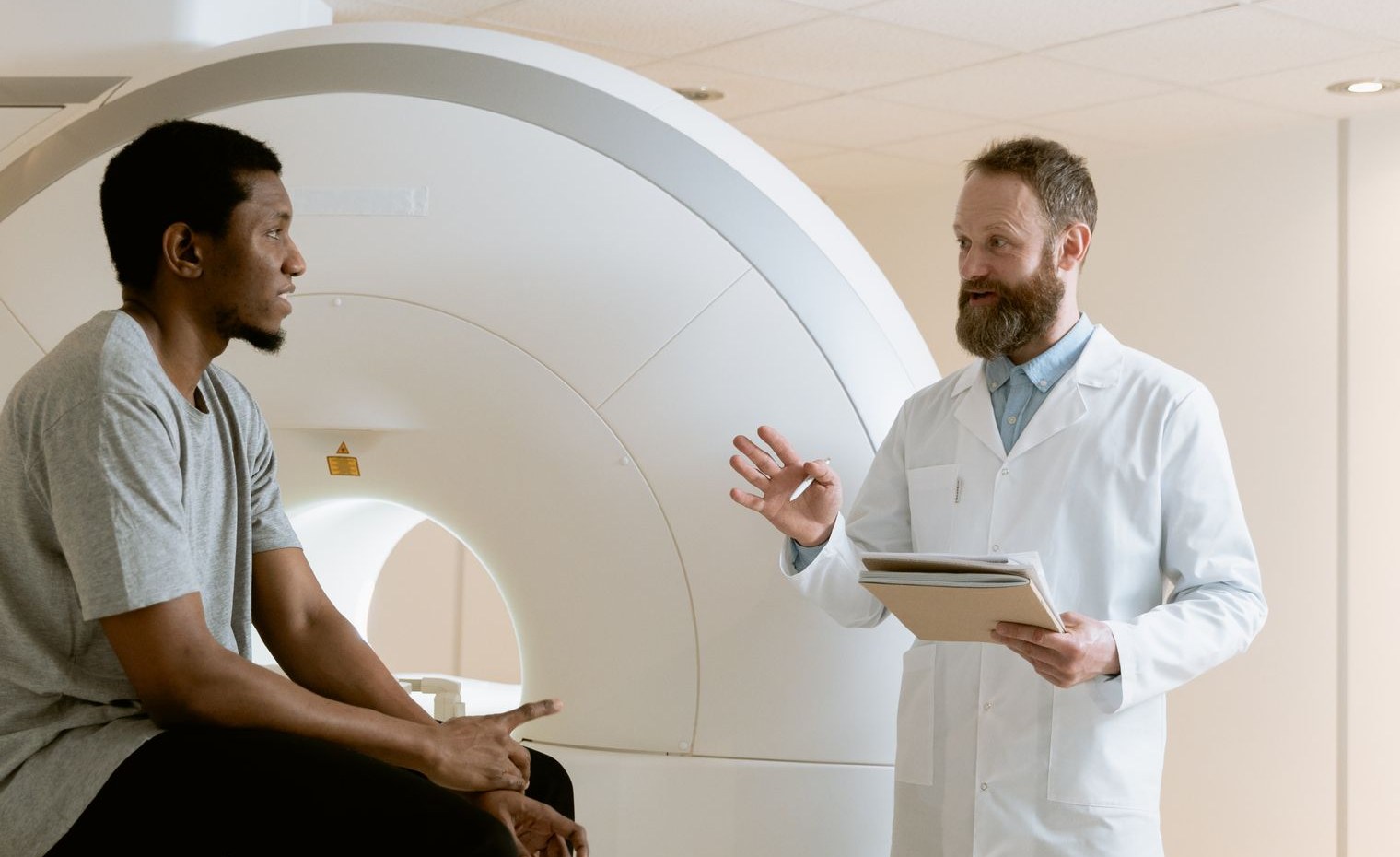 Doctor explaining scan findings to a patient beside an imaging scanner before kidney surgery