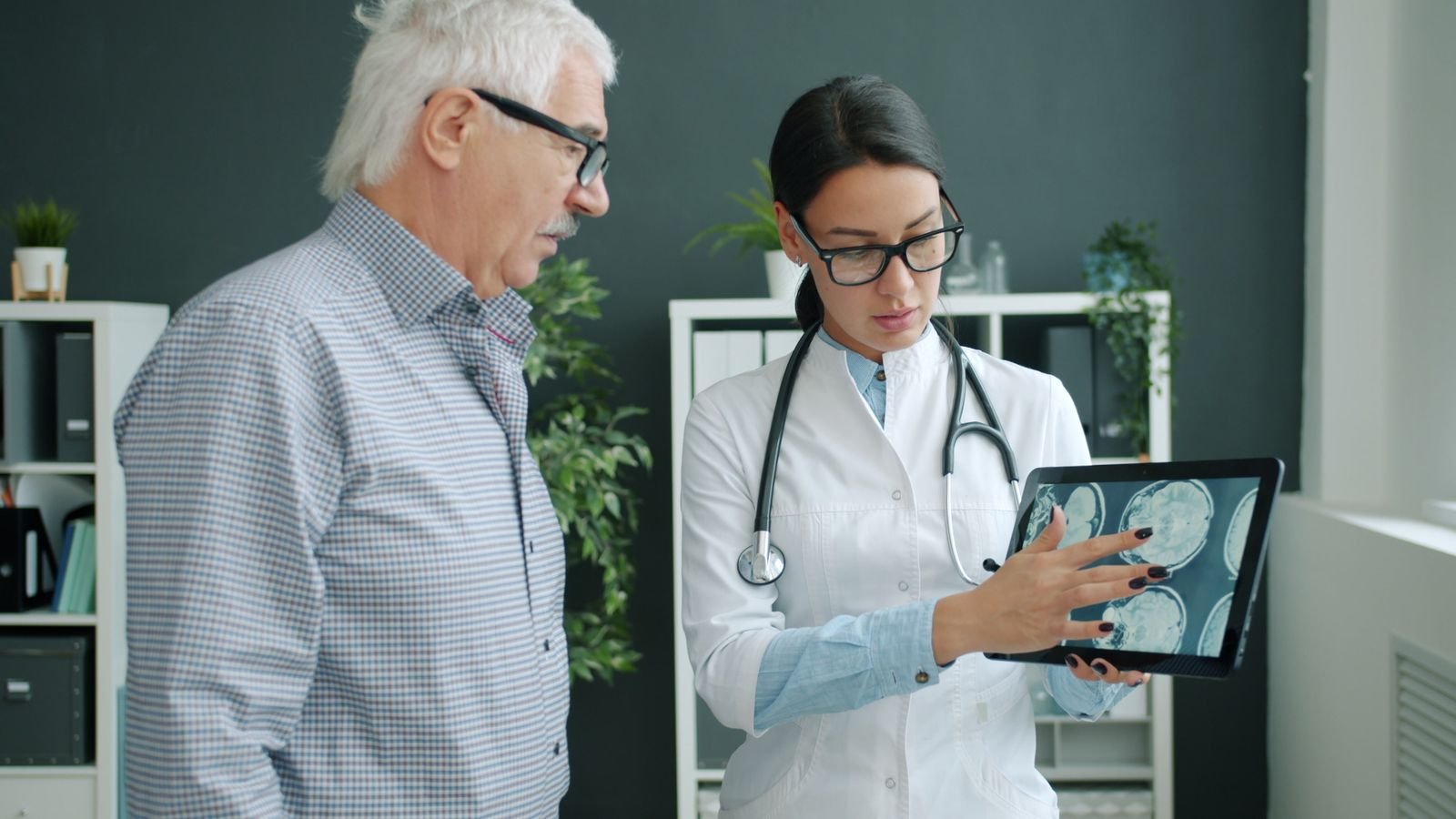 Single Port Robotic Surgery - doctor reviewing MRI images on a tablet with an older male patient